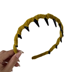Ginger velvet headband with black plastic teeth detail held against white background