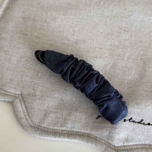 Close-up of a pleated navy blue denim fabric banana hair clip with a sturdy plastic structure