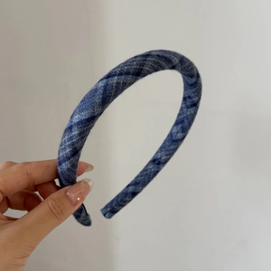 Detailed close-up of blue plaid pattern fabric covering a slim minimalist headband