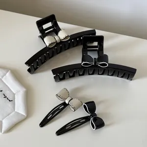 Détail des pinces à cheveux noeud en acétate noir et blanc avec coutures contrastées