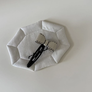 Pince à cheveux nœud minimaliste noir et blanc avec détails cousus main sur support blanc