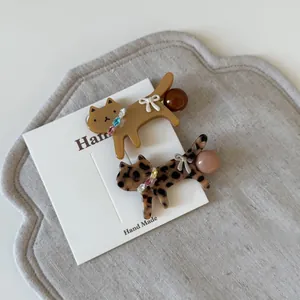Close-up of handmade cat hair clips in leopard and caramel tones on display card