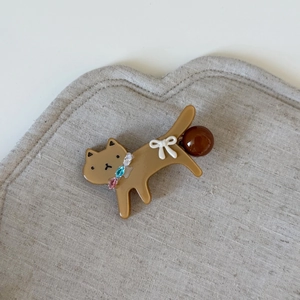 Cute brown resin cat hair clip with white bow and colorful rhinestones on grey fabric