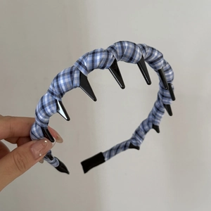 Détail d'un serre-tête en tissu à carreaux bleus avec dents antidérapantes et bord large