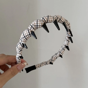 Détail d'un serre-tête vintage à carreaux marron et blanc avec des dents antidérapantes