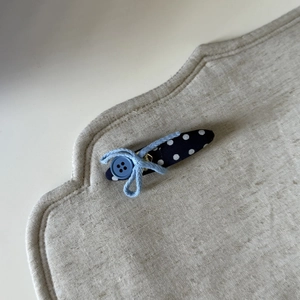 Handmade navy blue polka dot fabric hair clip with a light blue bow and button detail