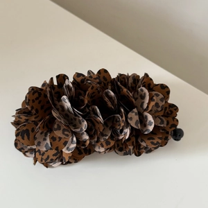 Detailed view of layered leopard print fabric flower hair clip with realistic textures