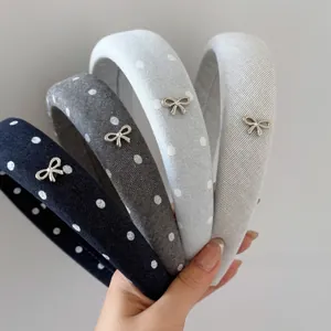 Detail view of denim polka dot sponge headbands in multiple colors with metal bow charms