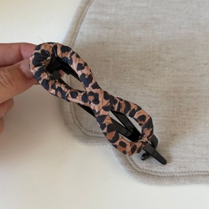 Detail view of a leopard print fabric hair claw clip with a stylish twisted design