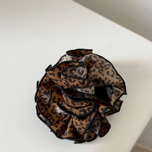 Close-up of leopard print chiffon hair clip with ruffled edges and black inner claw