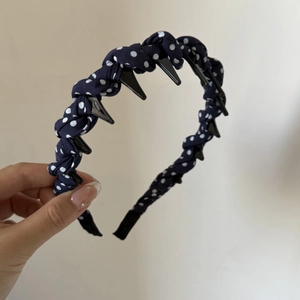 Detail of dark blue polka dot fabric headband with inner plastic grip teeth for secure hair