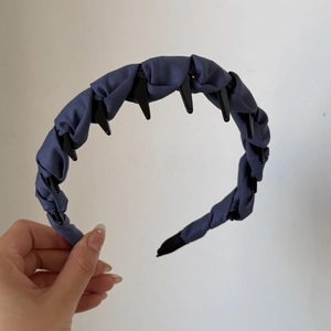 Gros plan d'un serre-tête bleu en tissu avec dents antidérapantes et design plissé élégant