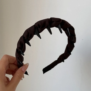 Détail d'un serre-tête en tissu marron foncé avec dents antidérapantes pour un maintien sûr