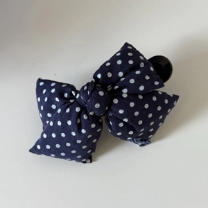 Close-up of navy blue polka dot bow hair clip with embroidered letter branding