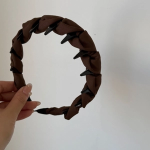 Détail du serre-tête en tissu marron torsadé avec dents antidérapantes à l'intérieur