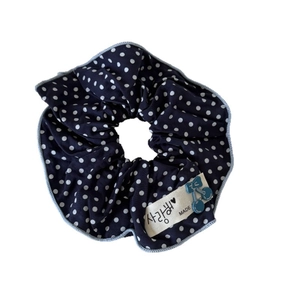 Navy blue polka dot hair scrunchie with a fabric tag and a light blue cherry pendant
