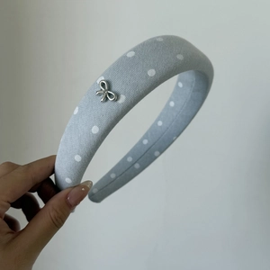 Detail of light blue polka dot denim headband with a small silver metal butterfly charm