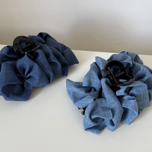 Vue détaillée des grandes pinces à cheveux bleu denim avec texture de tissu plissée