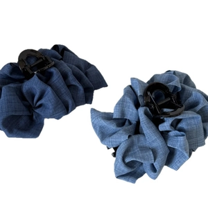 Paire de pinces à cheveux à volants bleu denim montrant la texture du tissu