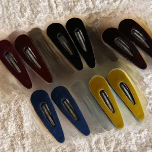 Detail of five pairs of colorful velvet flocking triangle snap clips on soft white fur