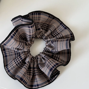 Close-up of dual-layer checkered fabric hair scrunchie with navy blue and brown pattern