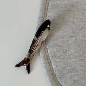 Detailed macro view of fish-shaped acetate hair clip with tortoise shell pattern and rhinestone