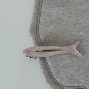 Detail of pink fish hair clip with resin texture and sparkling rhinestone eye detail