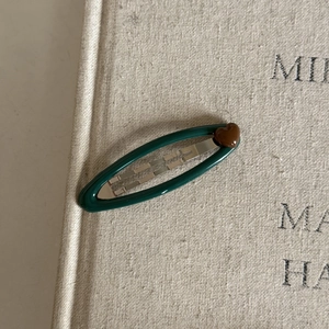 Detailed view of a navy blue oval hair clip with heart accent on a vintage book