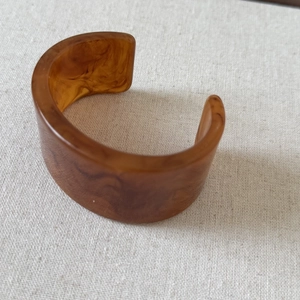 Detail view of amber resin cuff bracelet with tortoiseshell texture on linen background