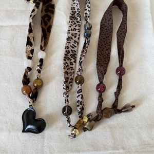 Brown leopard print scarf necklace with bohemian beads and heart pendant on burlap