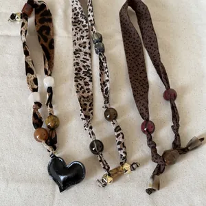Detail of leopard print scarf necklace with colored resin beads and heart pendant