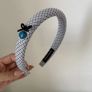 Detail of blue plaid fabric headband with black bow, bead and handmade woven label