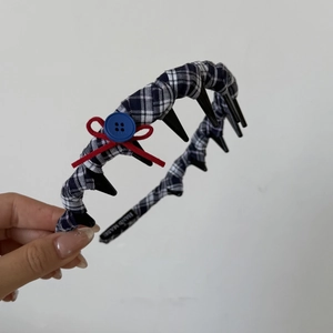 Détail d'un serre-tête à carreaux bleus avec nœud rouge et étiquette fait main