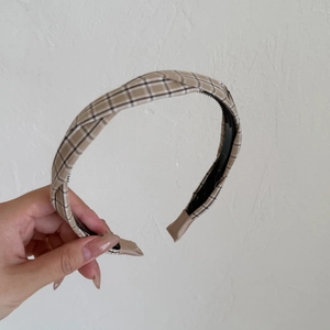 Detail of plaid headband featuring brown tartan fabric and black non-slip inner teeth