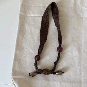 Close-up of vintage leopard print fabric necklace with red beads and horn-style pendants