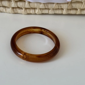 Macro detail of high-quality dark brown resin bangle with retro amber tortoise texture