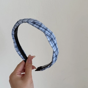 Close-up of blue and white gingham headband featuring a twisted knot and non-slip inner teeth