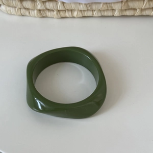 Close-up of an olive green irregular geometric acrylic resin bangle with glossy finish