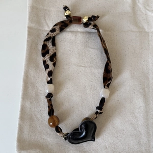 Detail of leopard print fabric necklace with amber beads and black heart pendant