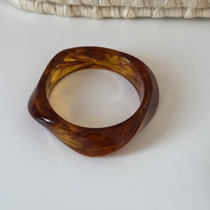 Macro view of wide irregular amber resin bangle with dark marble texture details