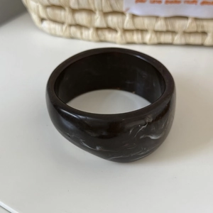 Detailed macro view of deep brown acrylic resin bangle with white marble texture