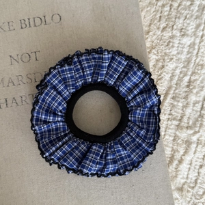Dettaglio ravvicinato di elastico scrunchie a quadretti blu navy con bordi a volant