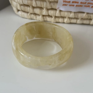 Macro shot of wide chunky acrylic resin bangle featuring marble cream pattern texture