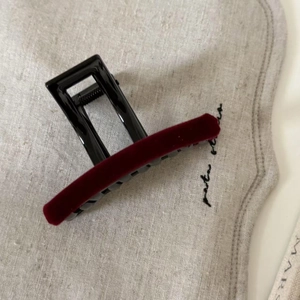 Detail of burgundy velvet hair claw clip with black metal spring on linen background