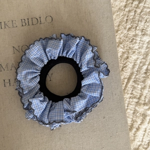 Dettaglio dell'elastico per capelli a scacchi blu navy con bordo grigio a onde rifinito