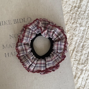 Dettaglio dell'elastico per capelli a quadretti con bordo rosso a volant e trama blu