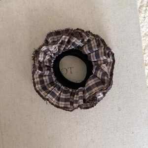 Dettaglio del tessuto a quadretti marroni dello scrunchie e dell'elastico resistente