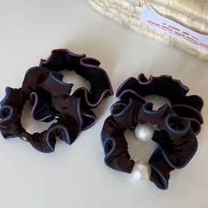 Detail of four-piece hair scrunchie set with contrast edges and elegant faux pearls