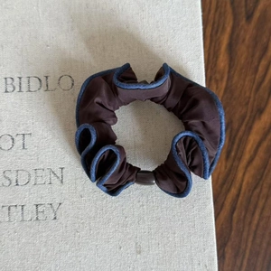 Brown scrunchie with blue denim edges on vintage beige book background for ponytail styling