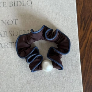 Brown and blue scrunchie with large white pearl accent on a vintage fabric background